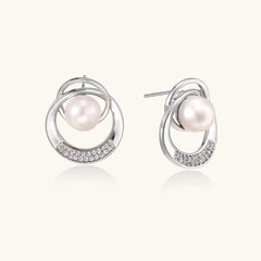 White gold-plated brass earrings with circular design, freshwater pearl center, and diamond accents