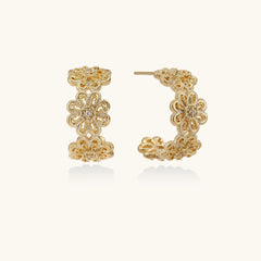 Gold hoop earrings with intricate three-dimensional floral filigree pattern in 14K gold plated brass on cream background