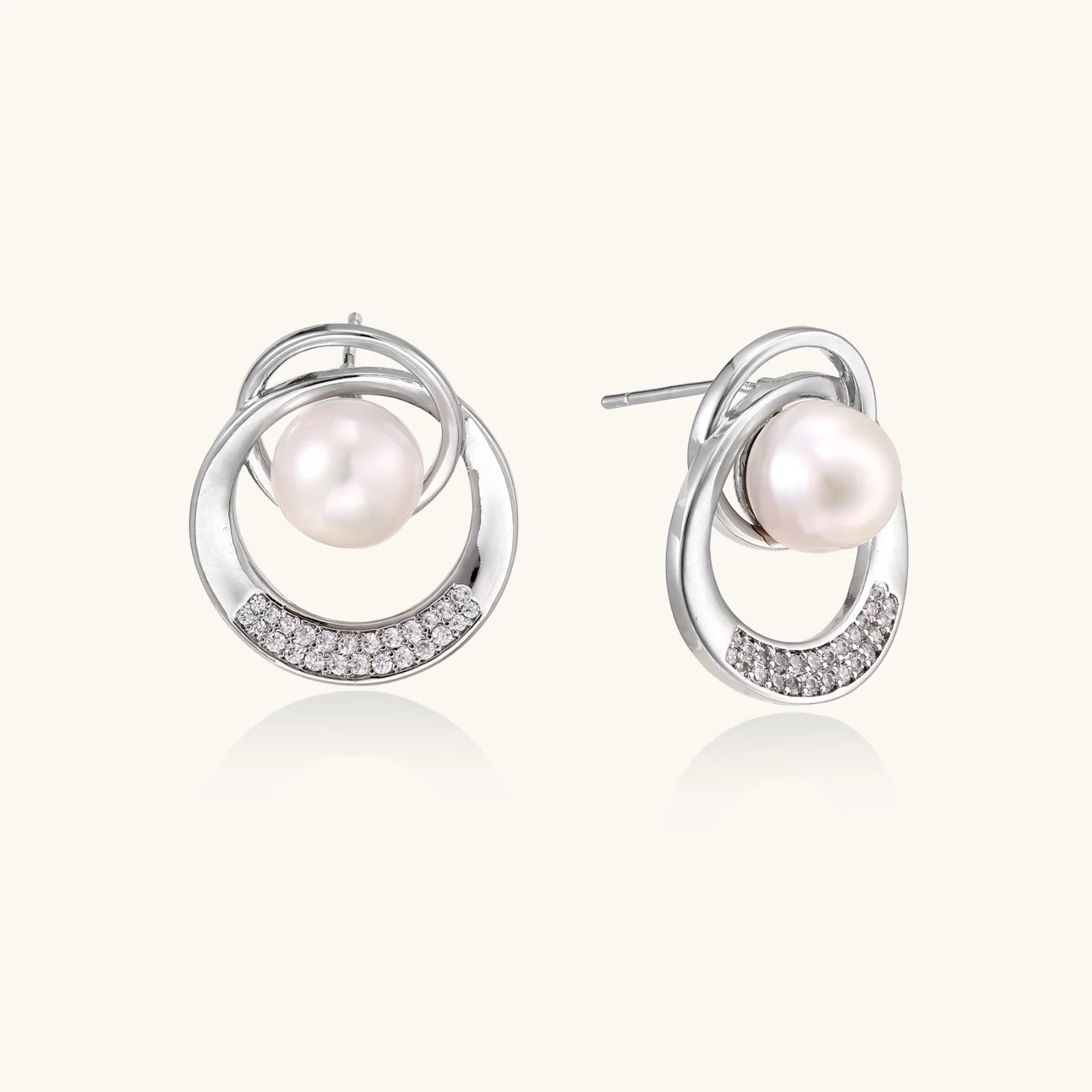 White gold-plated brass earrings with circular design, freshwater pearl center, and diamond accents