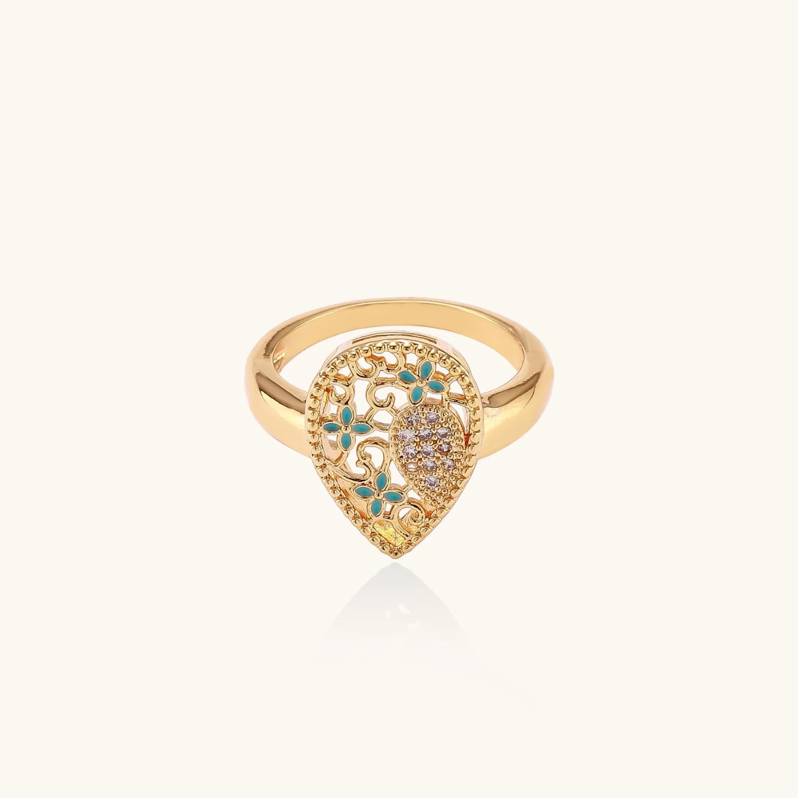 Teardrop-shaped gold-plated ring with turquoise enamel flowers and crystal pavé detail on cream background