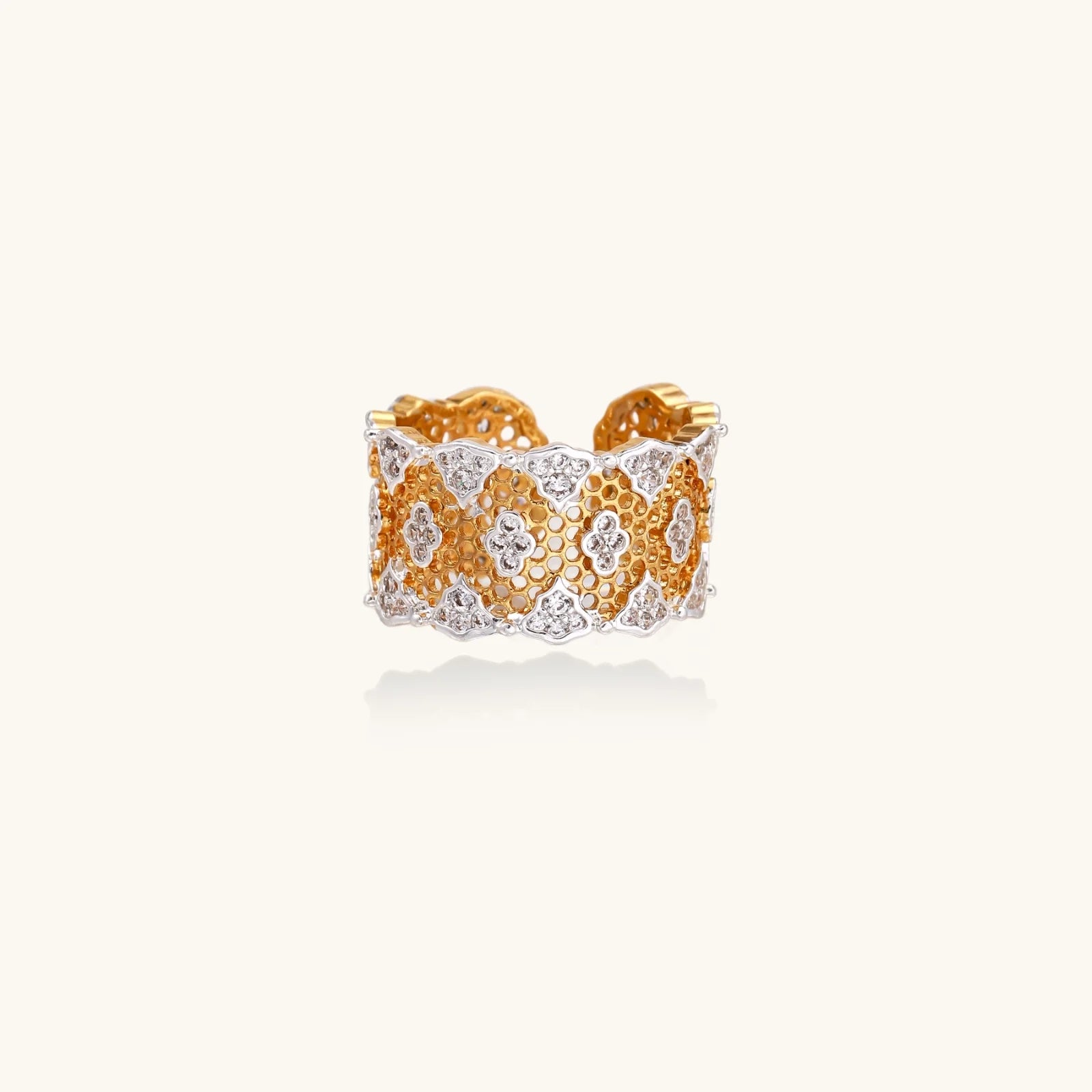 Two-tone gold and silver lattice ring with clover pattern and crystal accents on white background