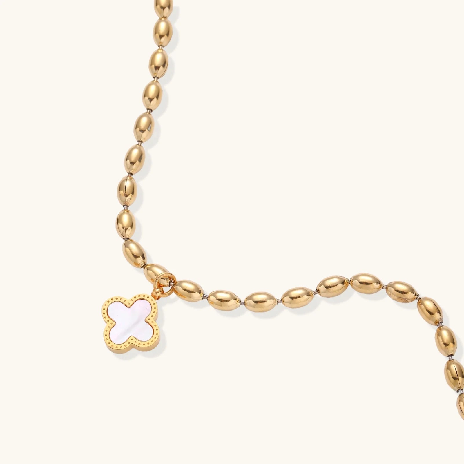 18K gold-plated oval bead chain bracelet with quatrefoil clover charm featuring mother of pearl inlay on cream background